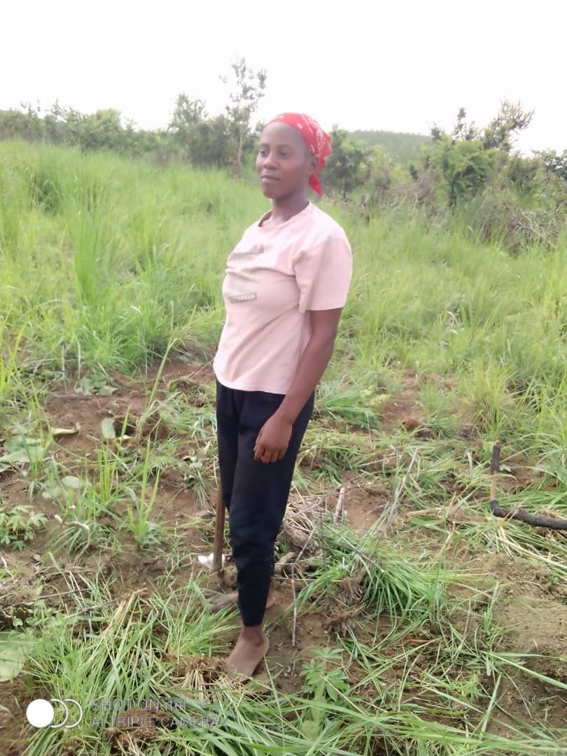 Une femme en chemise rose sur une parcelle agricole.